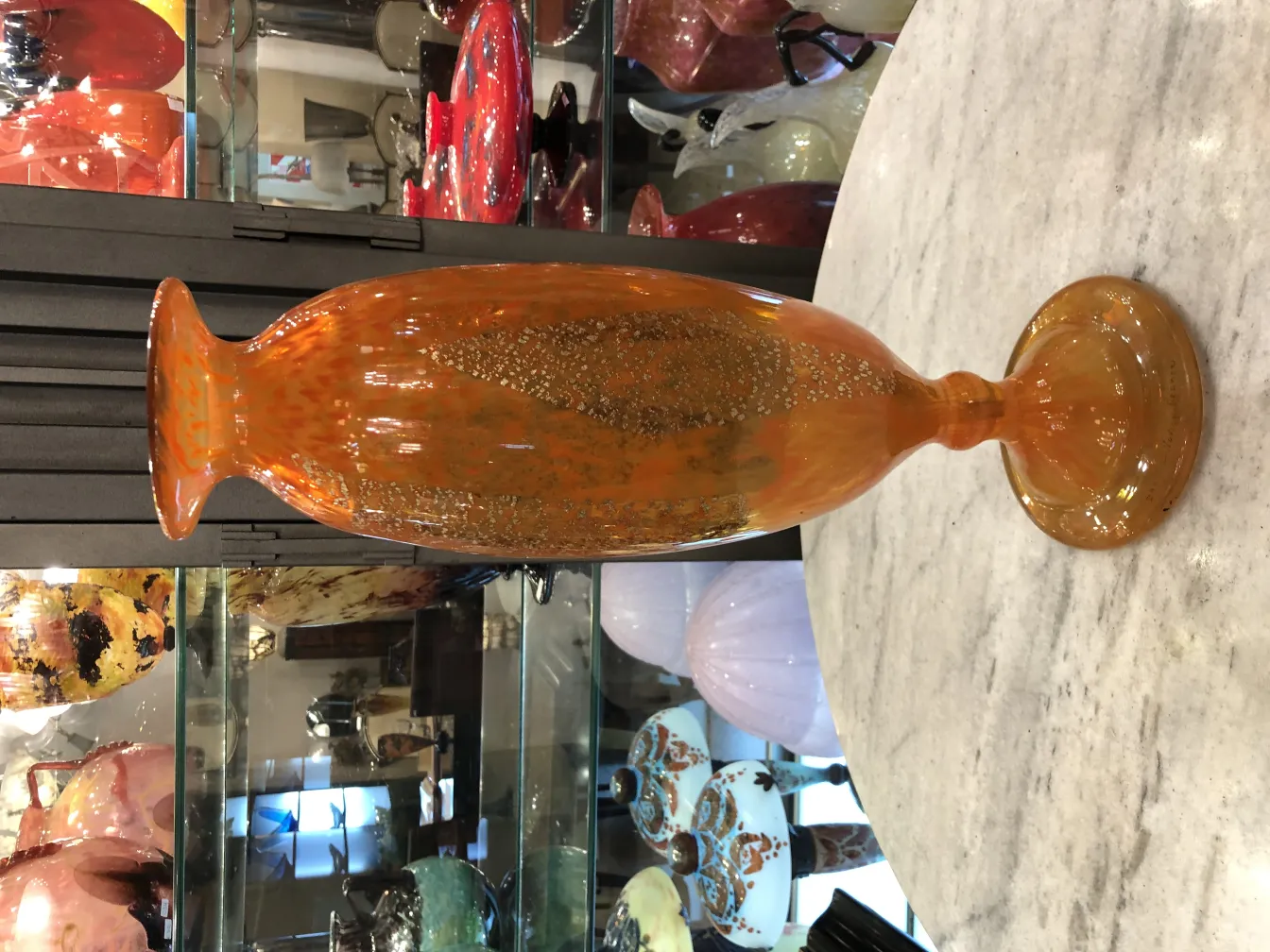 Colorful signed glass vase on reflective background