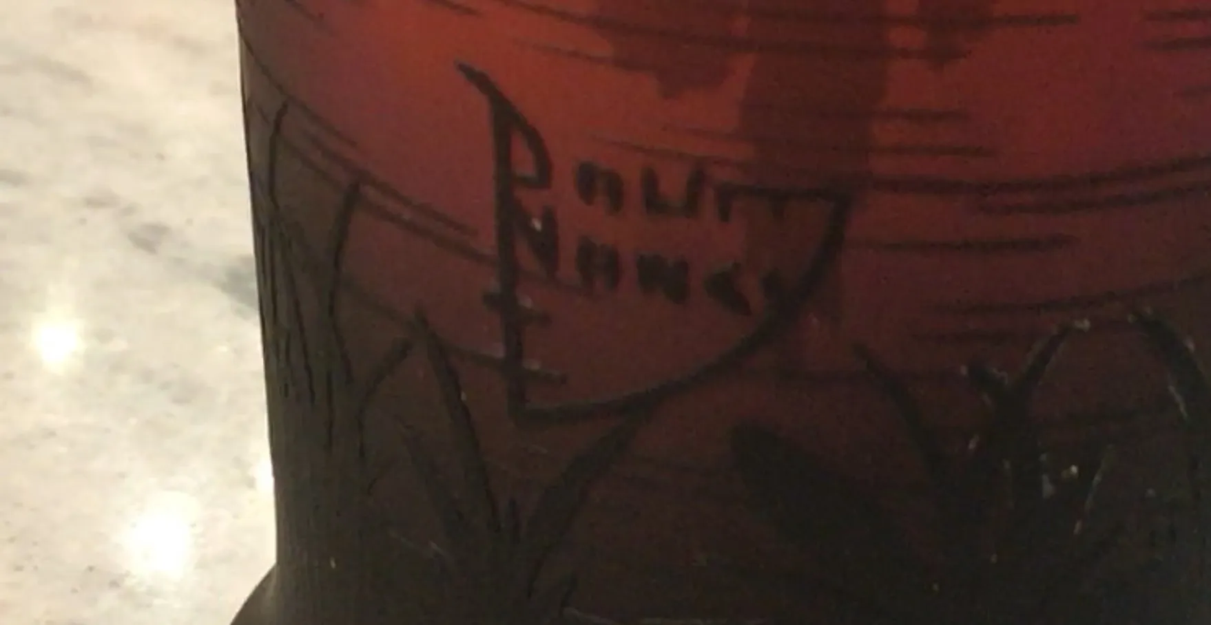 Verre signé par Daum Nancy avec des détails de conception uniques en couleur et forme, sur une surface élégante.