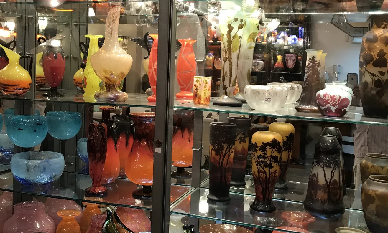 colección de antigüedades en vitrina con vidrio firmado, varias formas y colores