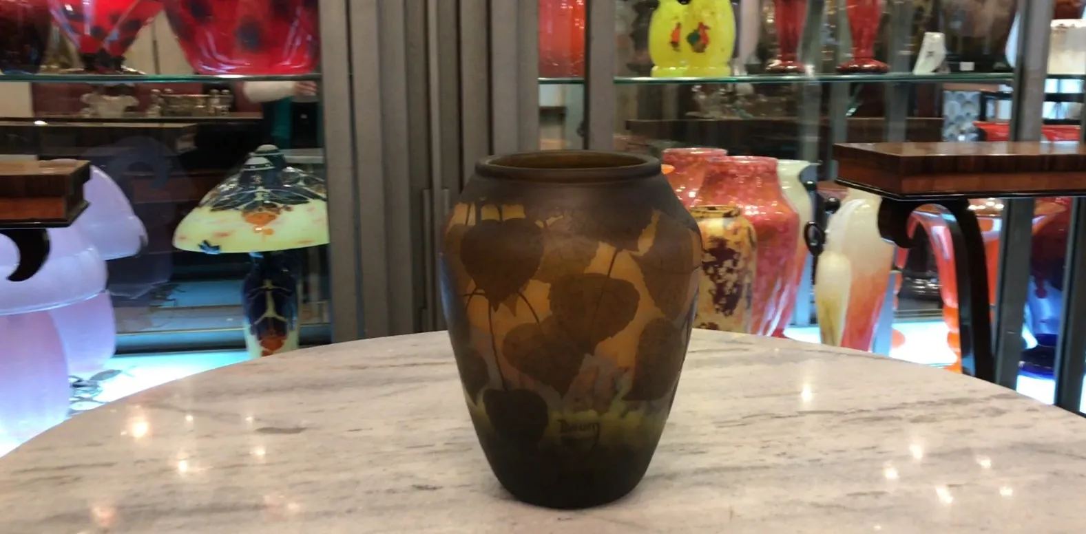 Vaso antigo com folhas esculpidas e tons escuros.