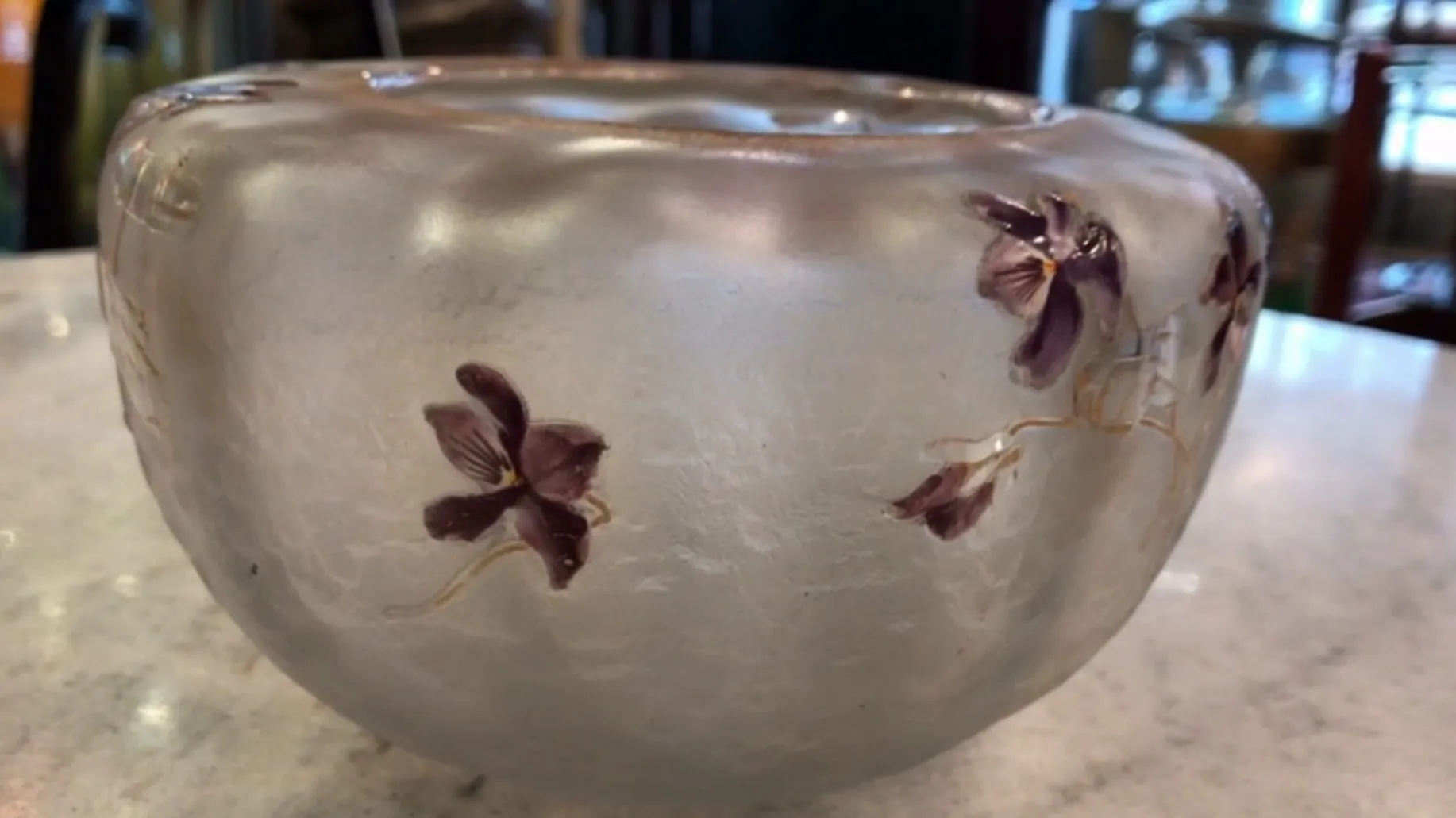 Visão lateral de um vidro assinado Daum Nancy antigo com decorações florais