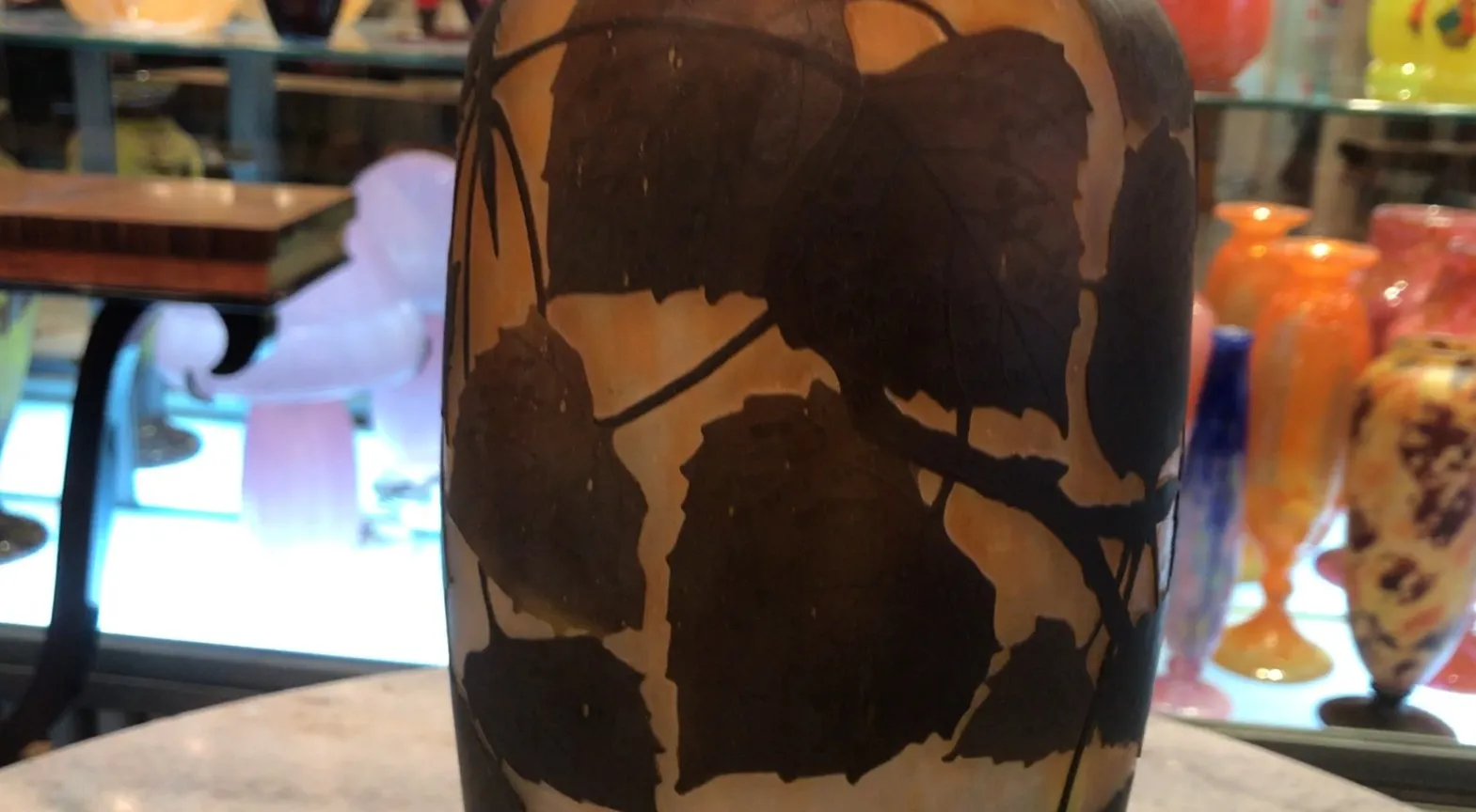 Antique piece with dark leaf designs on glass. Light background with distinctive details.