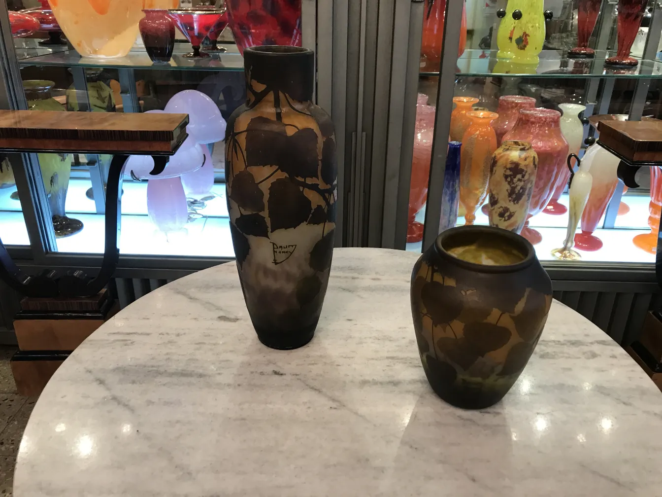 Vase ancien signé Daum Nancy avec motif floral, couleur sombre, exposé dans une vitrine