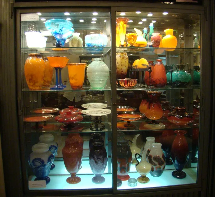 Collezione di antiquariato con vetro firmato Daum Nancy in esposizione, varietà di colori.