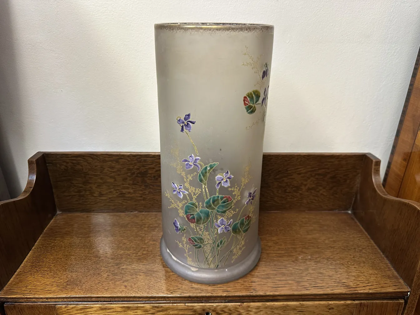 Vase en verre ancien signé Daum Nancy, décoré de fleurs violettes sur fond clair.