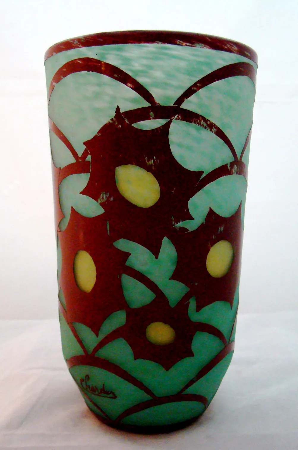 Signed glass Charder with floral design in green and red tones, bright background.
