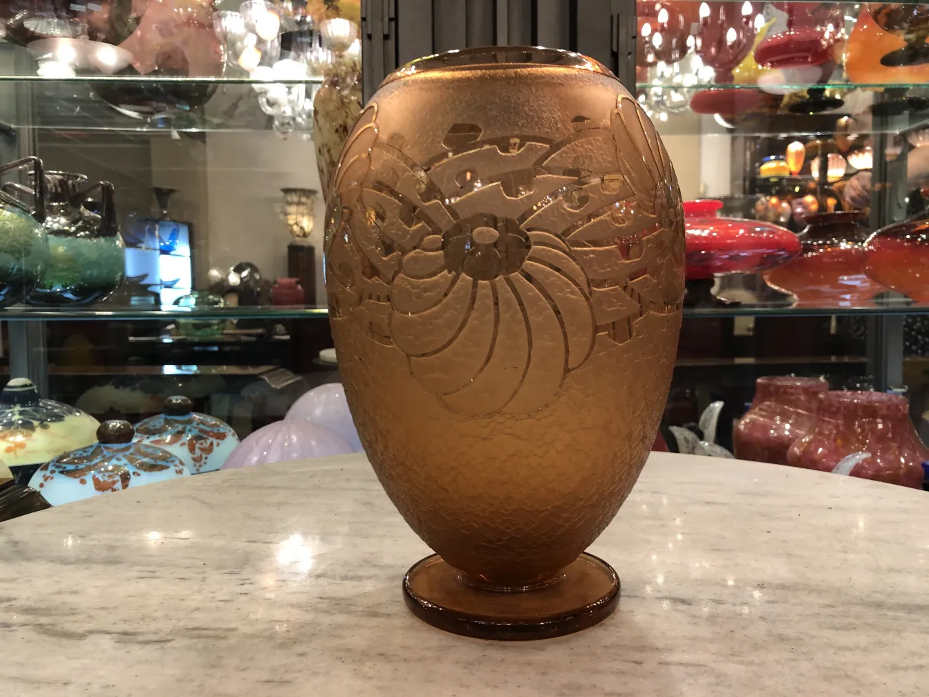 Vidrio firmado Charder con diseño detallado y forma ovalada, exhibido en tienda de antigüedades.