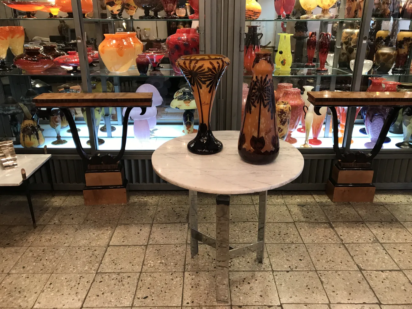 Verre signé Charder exposé parmi des antiquités colorées.