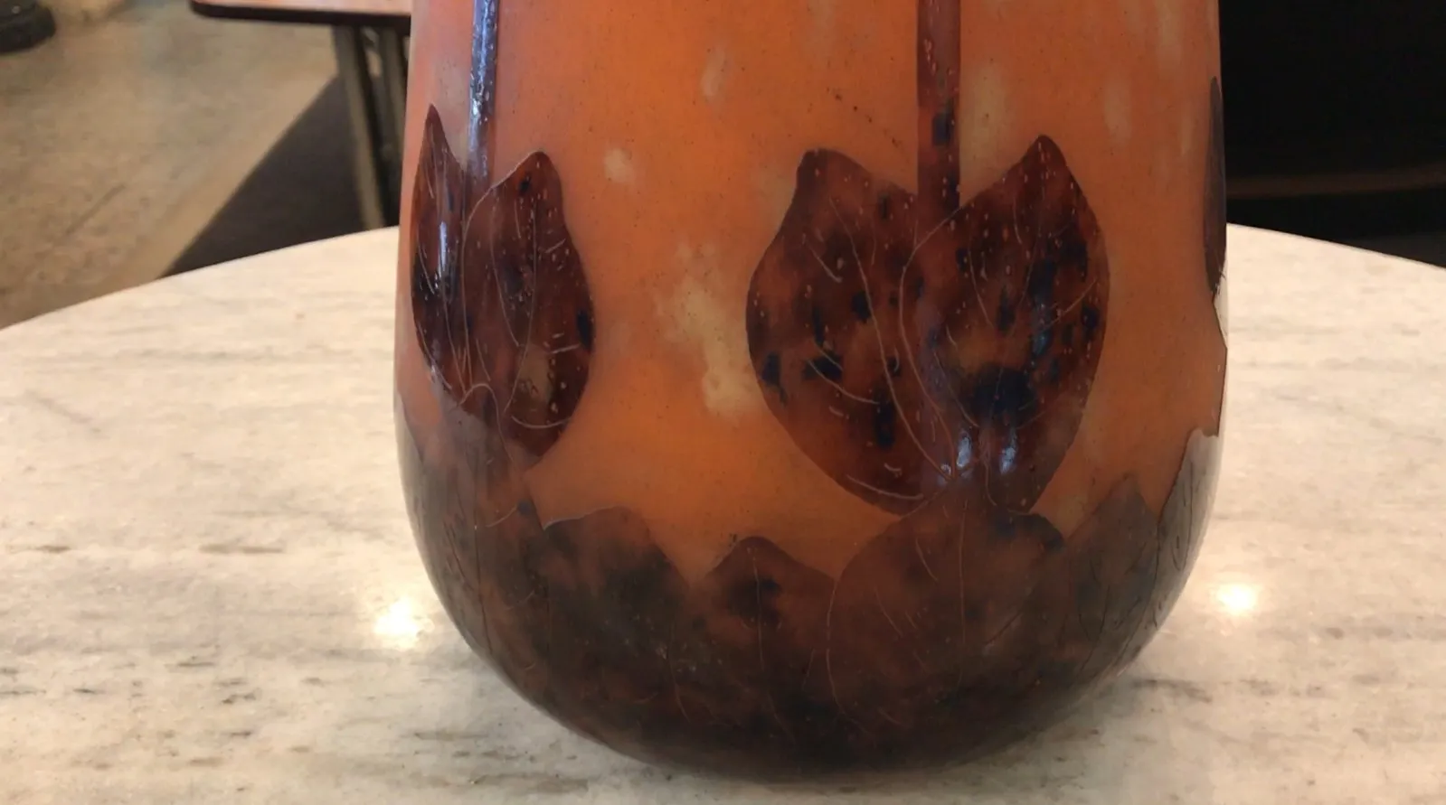 signiertes Glas Charder mit Blattmuster auf orangefarbenem Hintergrund