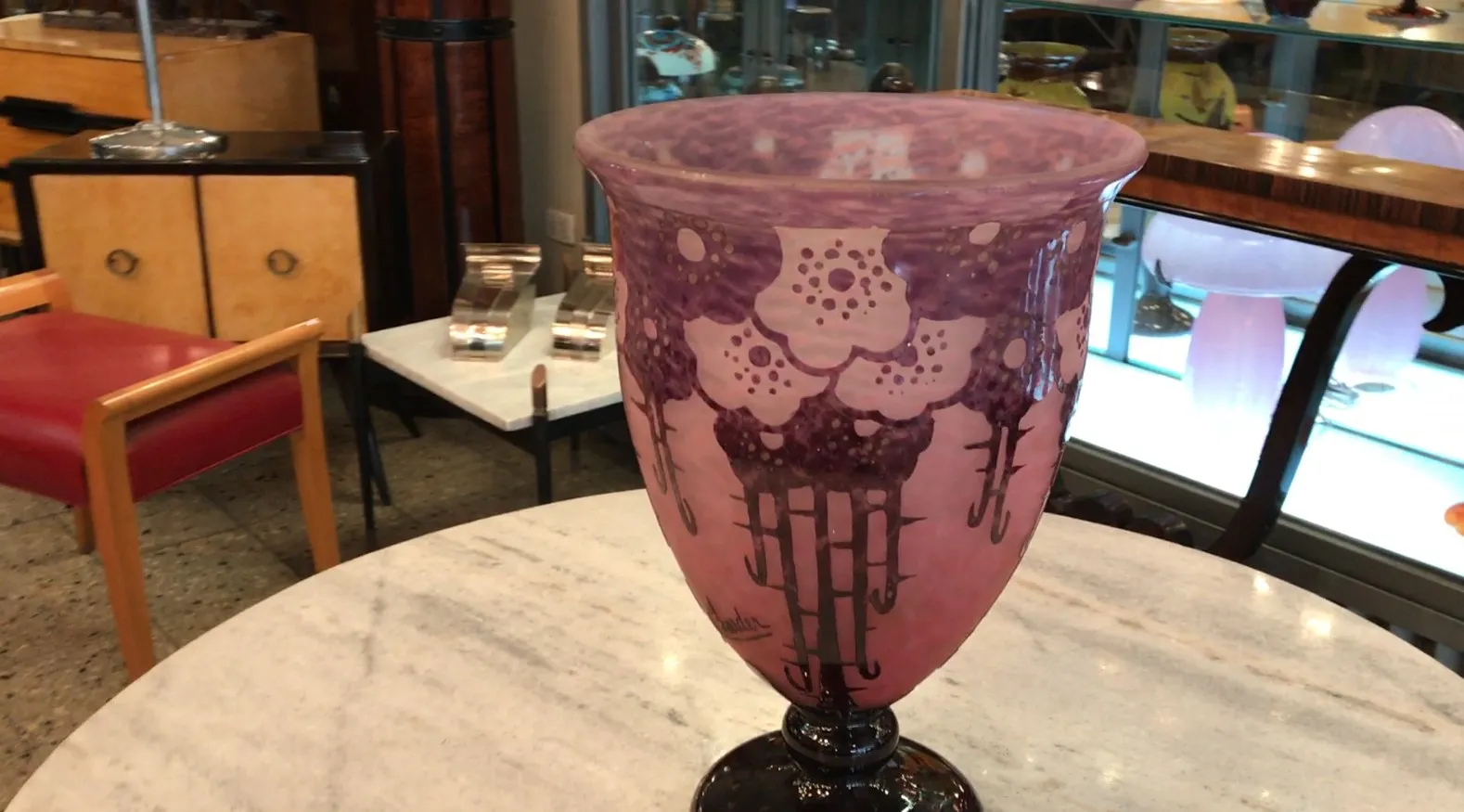 Vaso antiguo firmado Charder con detalles en violeta sobre fondo rosa.