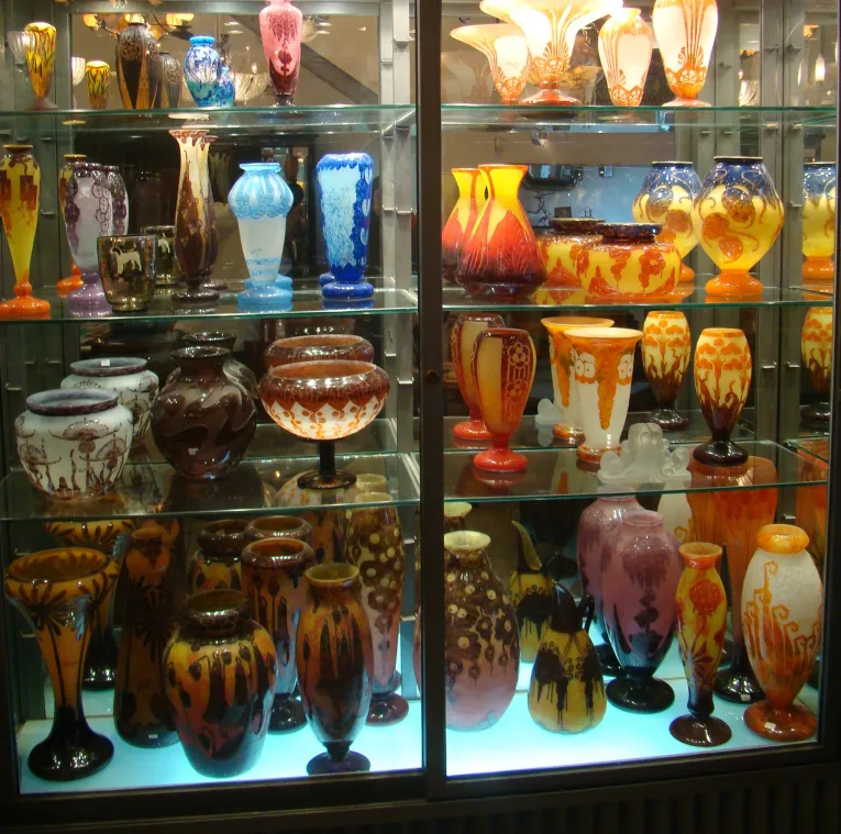 Colección de antigüedades con vidrio firmado por Charder en vitrina.