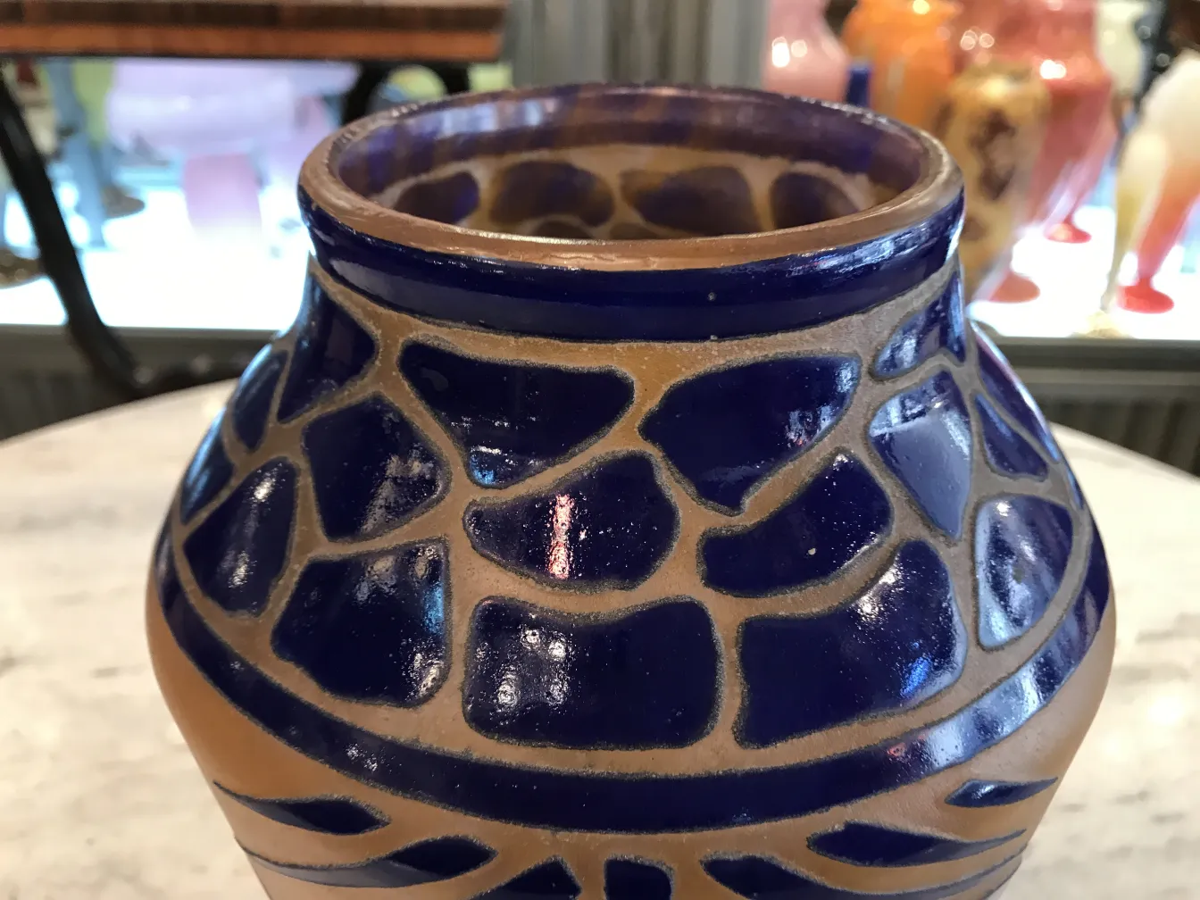 Vase antique avec un design bleu et beige, pièces décoratives en arrière-plan.