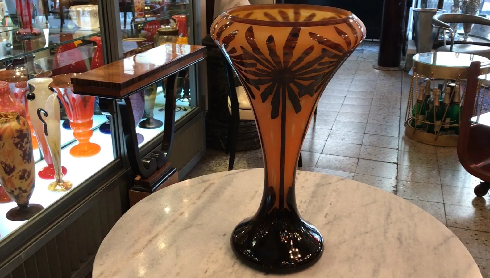 Verre signé Charder dans un cadre d'antiquités avec d'autres objets décoratifs.