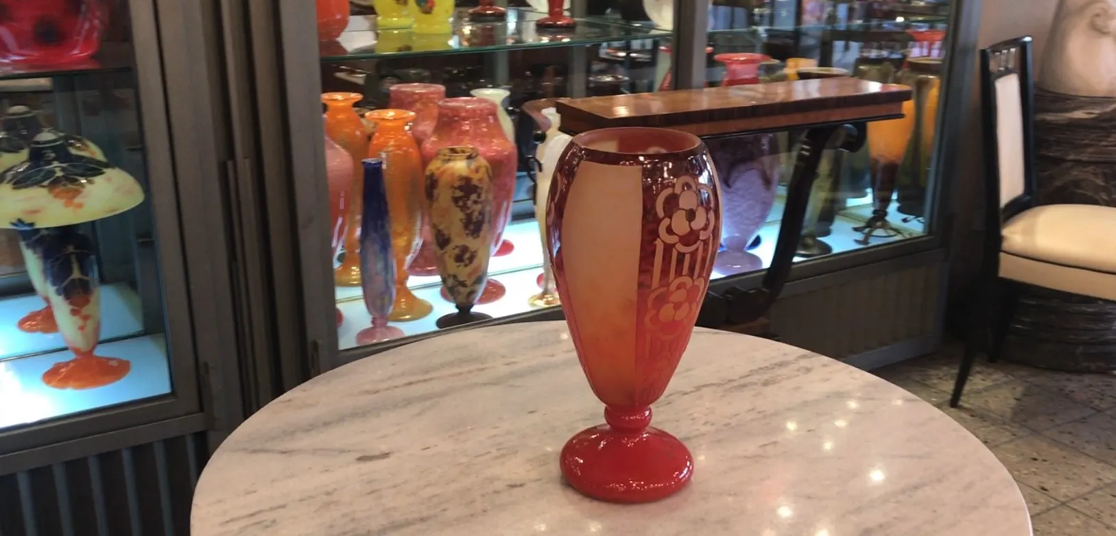 Vaso assinado por Charder com design floral, em um ambiente de antiguidades.
