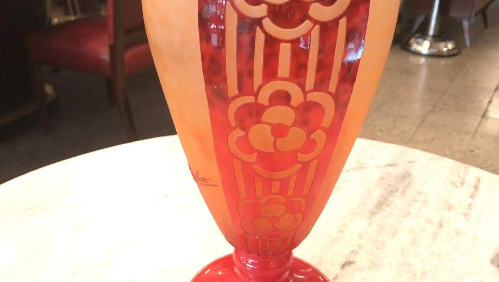 Vidrio antiguo firmado de Charder con diseño floral, rojo y naranja, en un entorno acogedor.