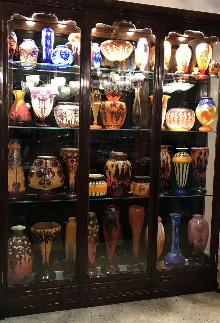 Vitrina con antigüedades de vidrio firmado Charder de varios colores y formas.