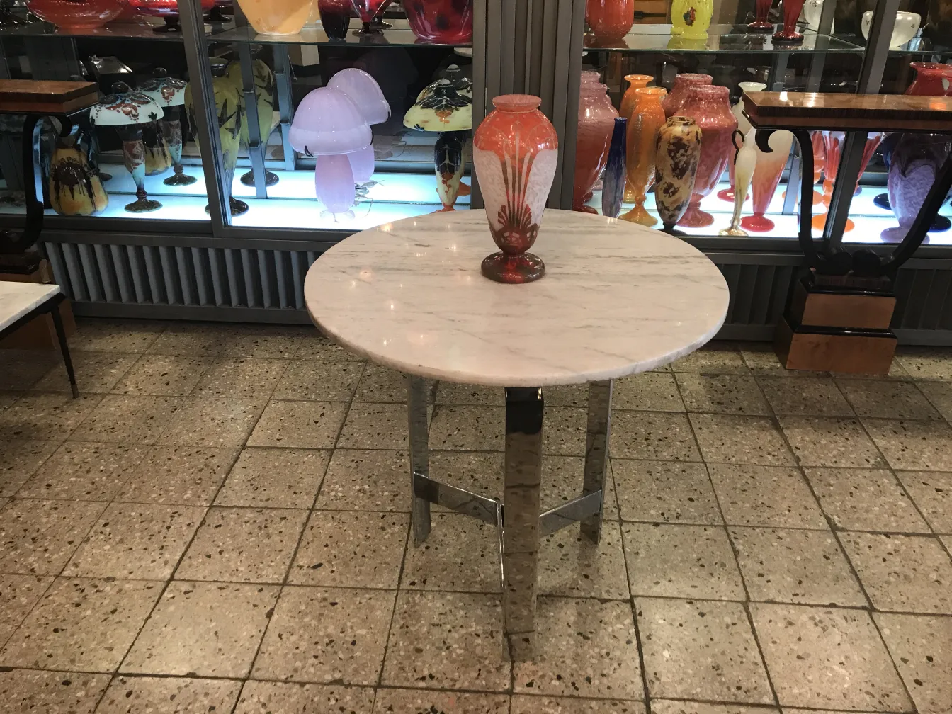 Verre signé Charder antique sur table, avec des vases colorés en arrière-plan.