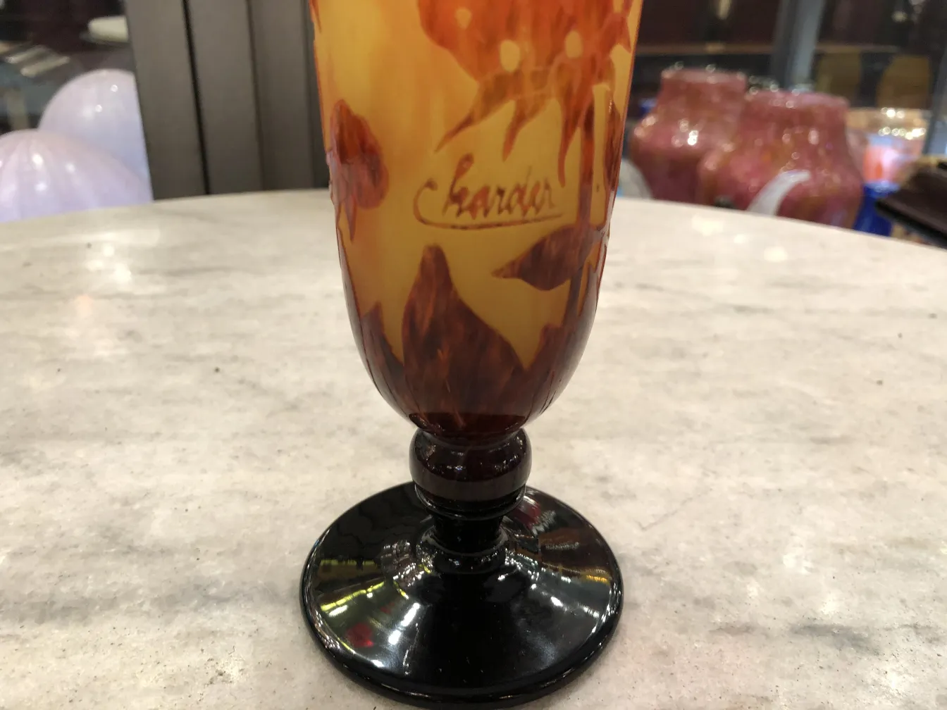 Antikes signiertes Glas Charder mit warmen Farben, hellem Hintergrund.