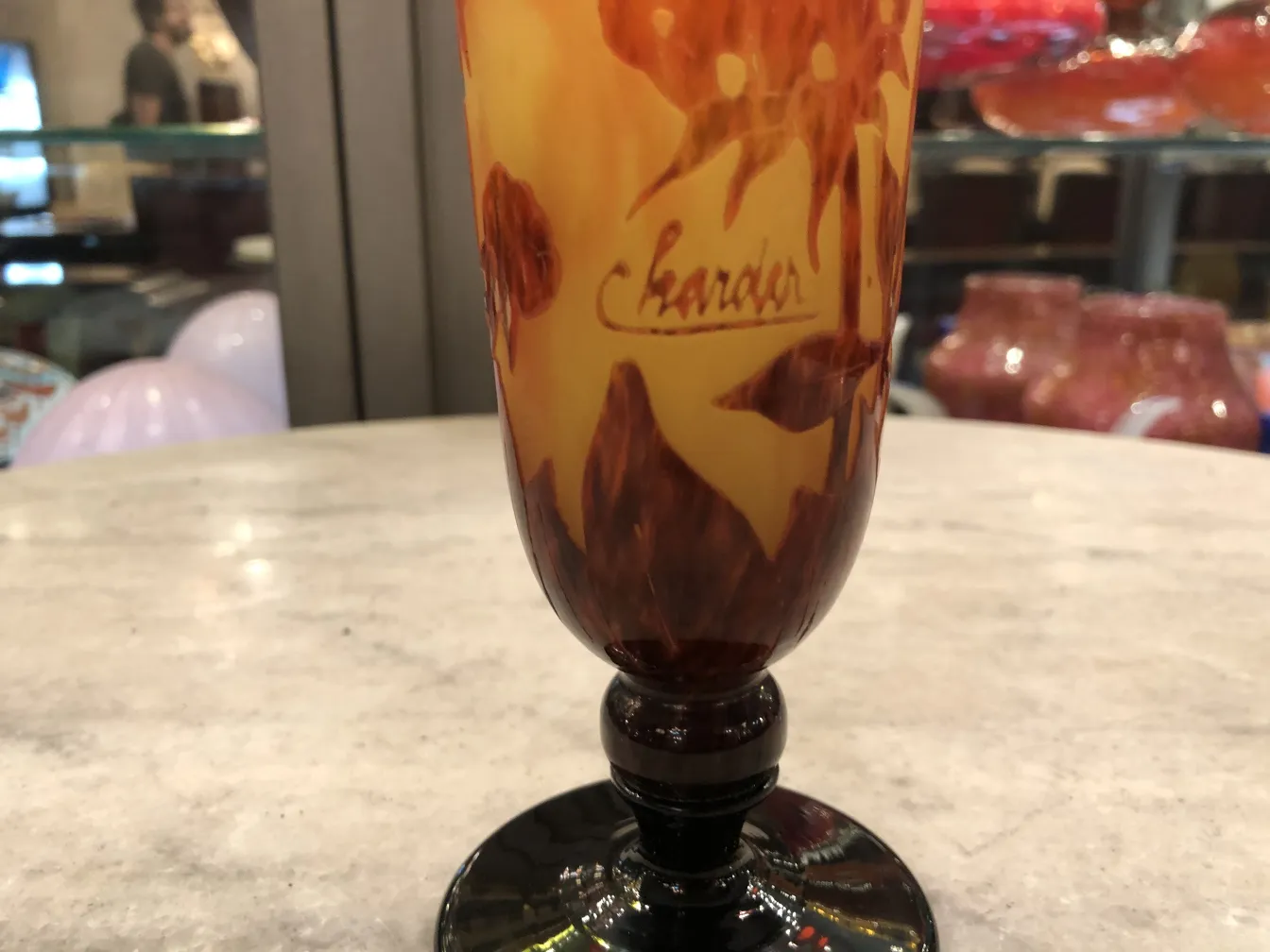 Signiertes Glas mit einem bunten Design in Orange und Braun.