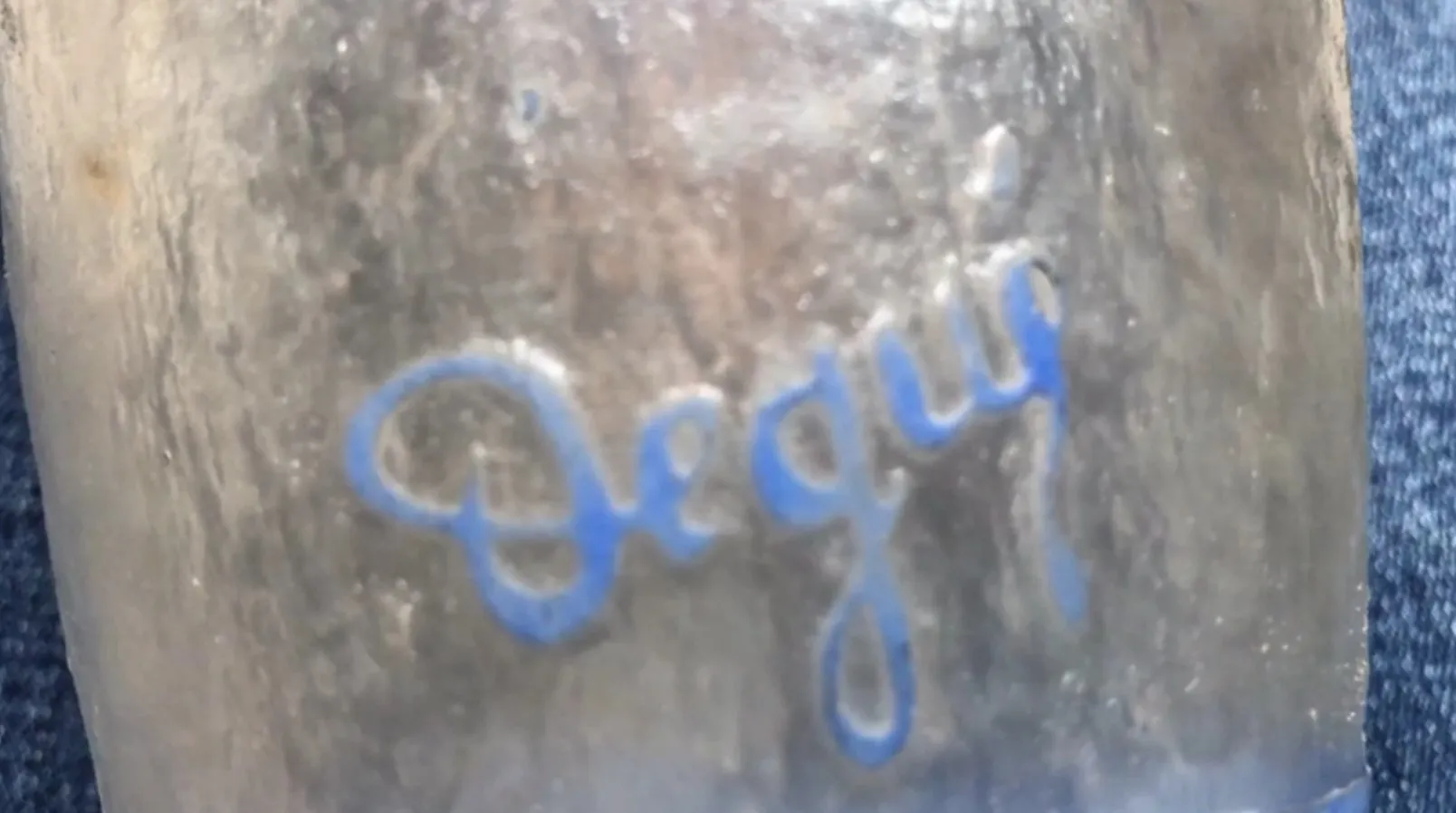 Vidrio antiguo firmado Degué con estampado en azul, ambiente cálido.