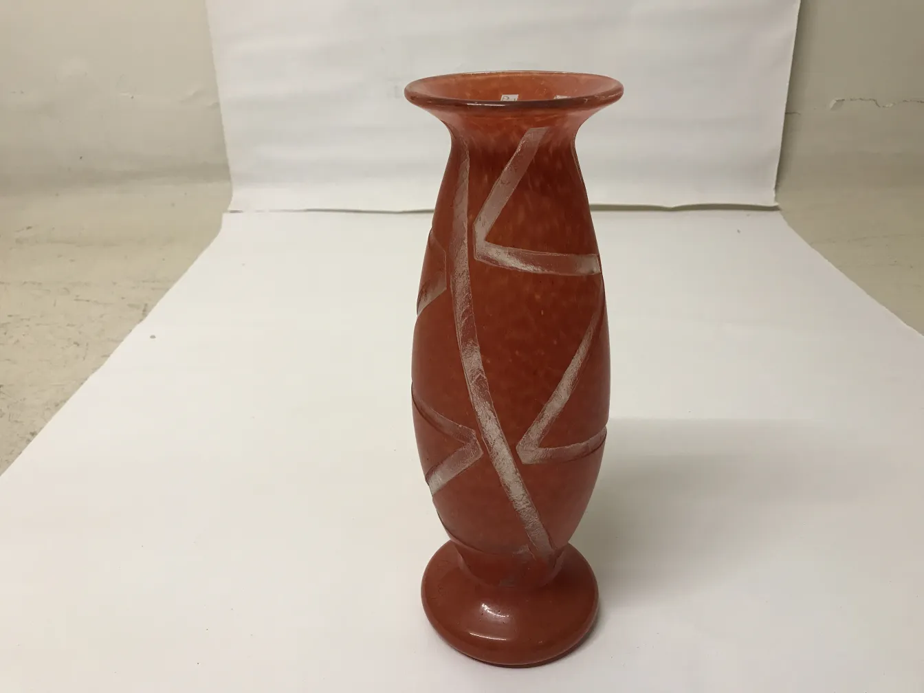 Antigüedad con forma de jarrón en tonos terracota, líneas decorativas.