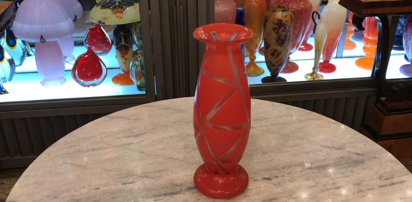 decorative and antique signed Degué glass in orange, featuring distinctive design, surrounded by other glass pieces on display
