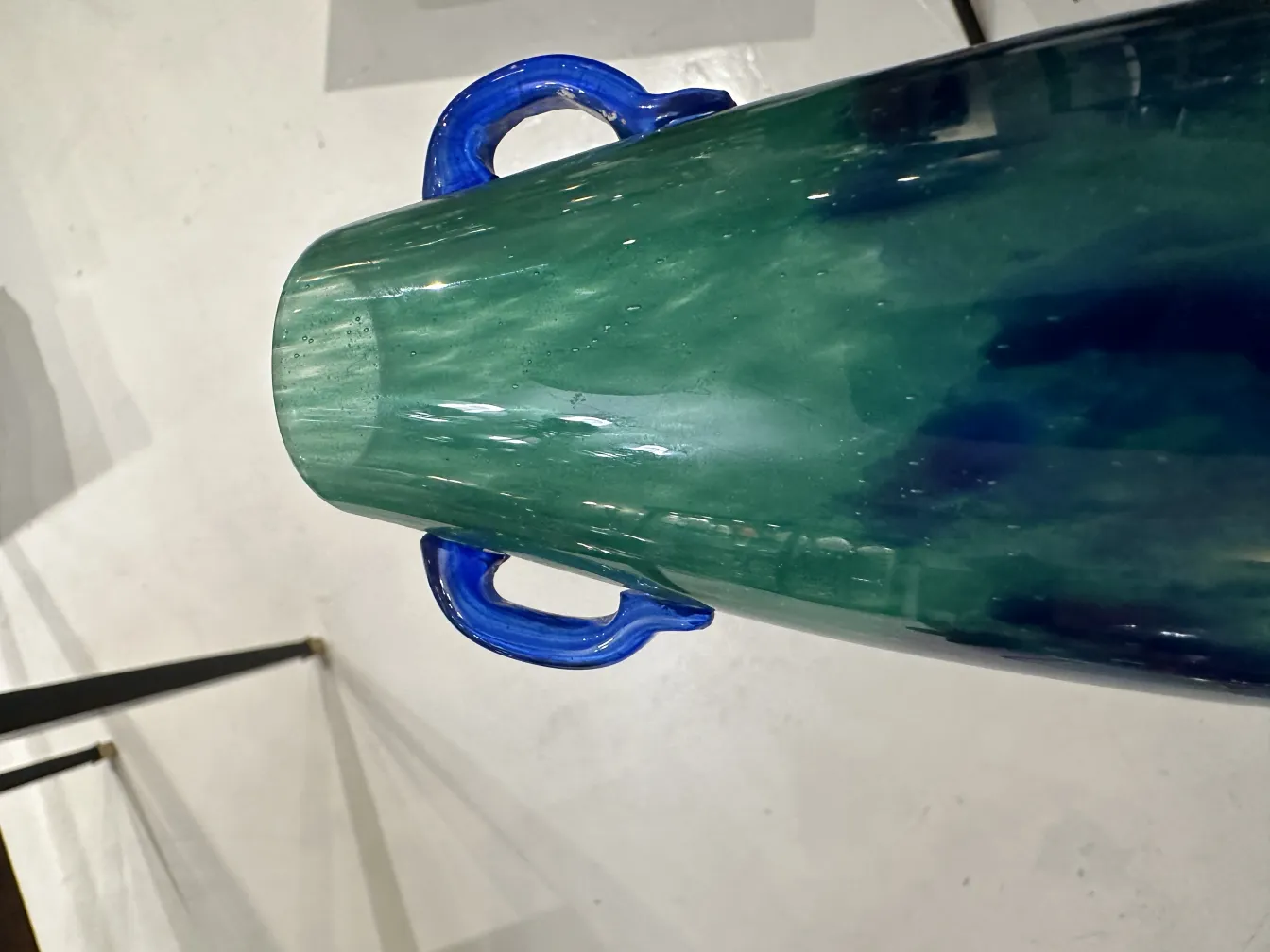 Visão superior de um vaso de vidro assinado Degué com alças azuis e cor verde.