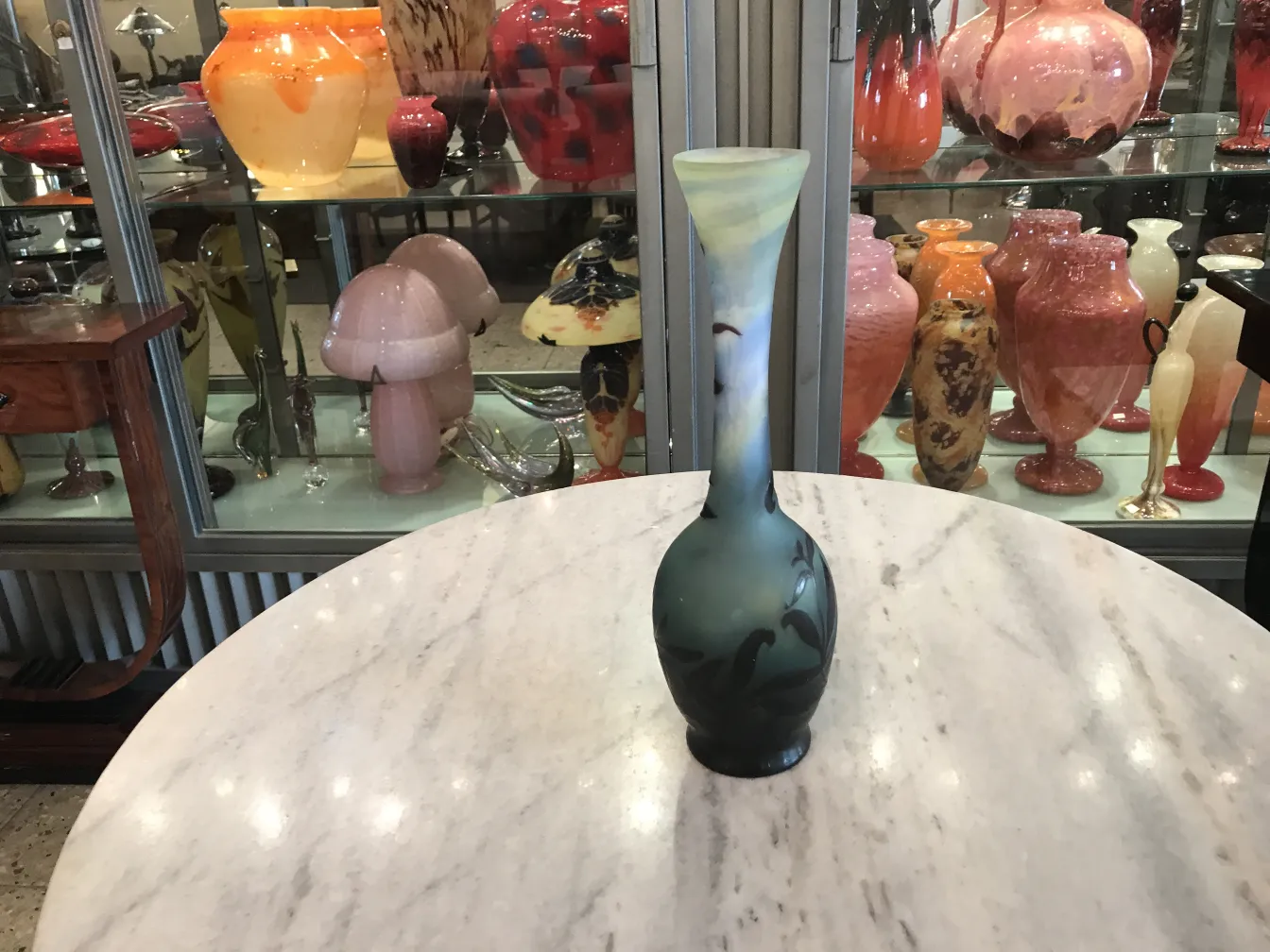 带签名的古董玻璃gallé装饰品，桌子上还有其他玻璃物品作为背景。