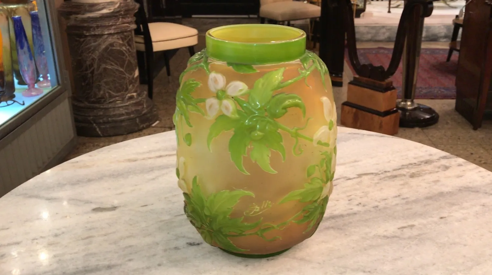 SIGNED GLASS Gallé featuring green floral design on light background, displayed in an antique setting.