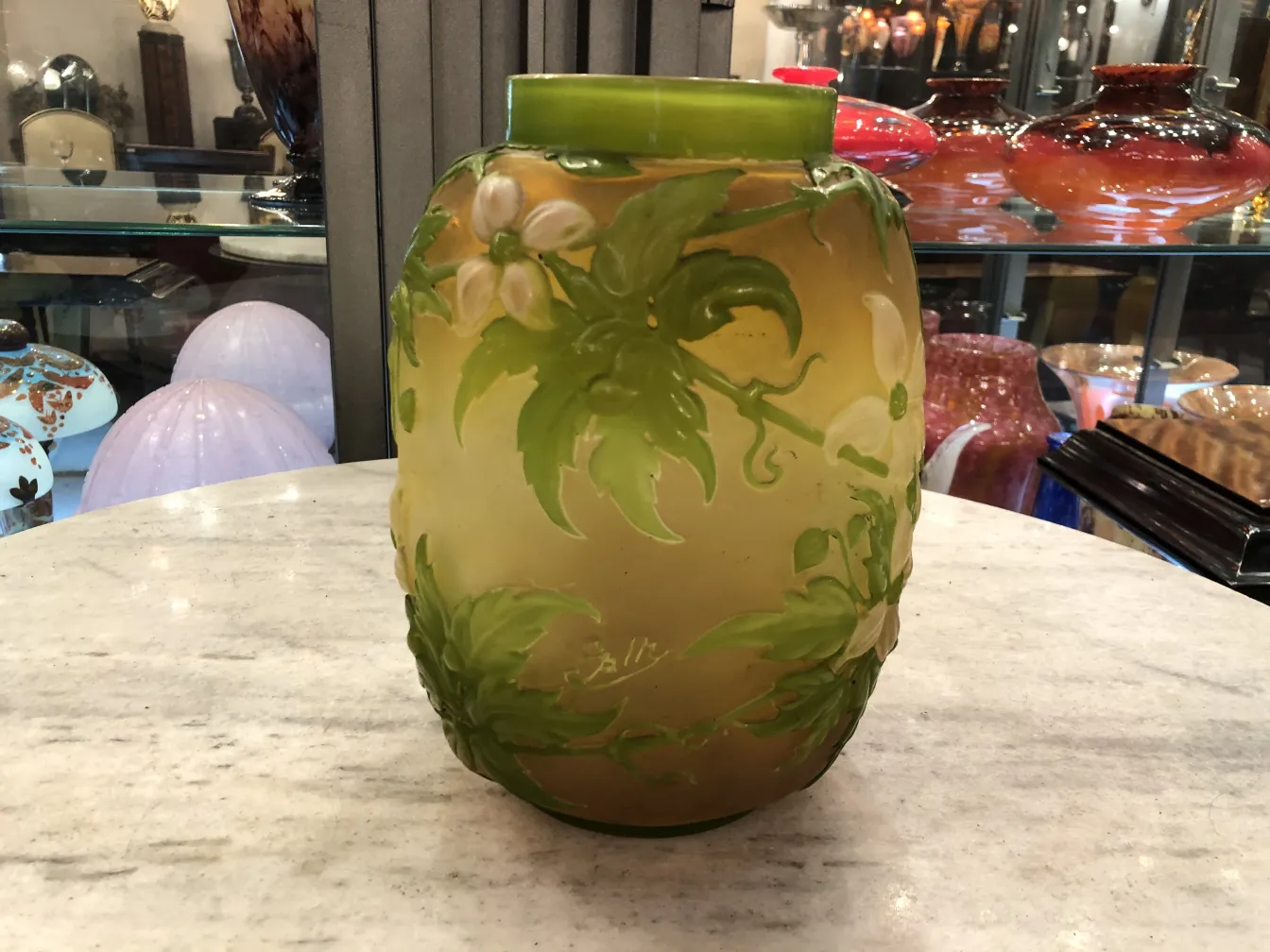 antikes Glasgefäß mit floraler Dekoration von Gallé auf hellem Hintergrund, neben anderen Glasartikeln