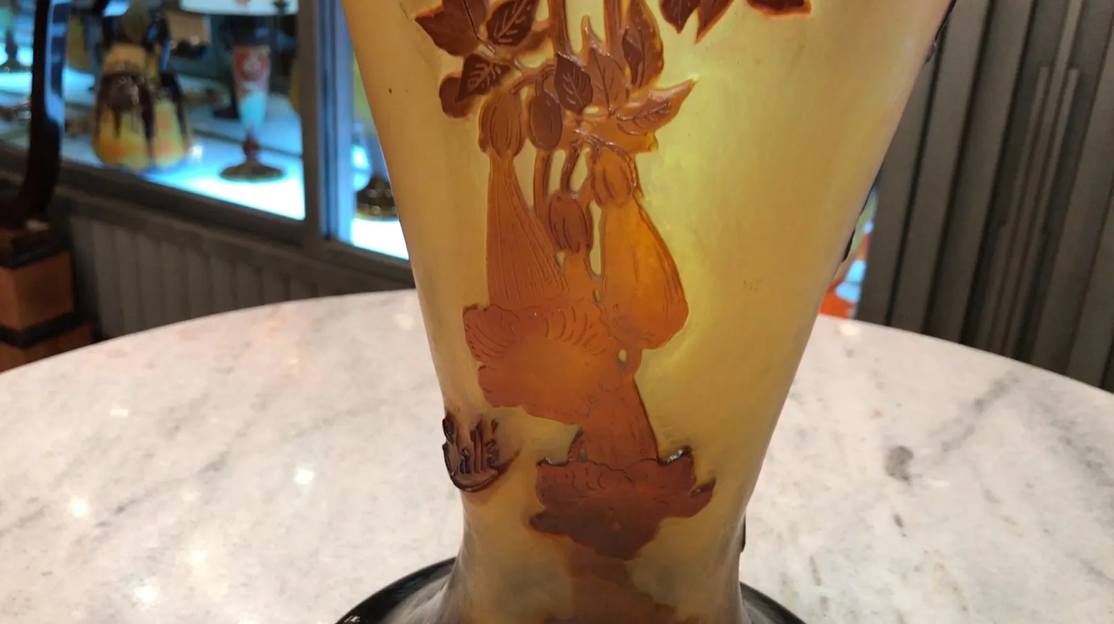 Vidrio firmado Gallé con diseño de flores en tonos dorados y marrones sobre fondo claro, parte de una colección de antigüedades.