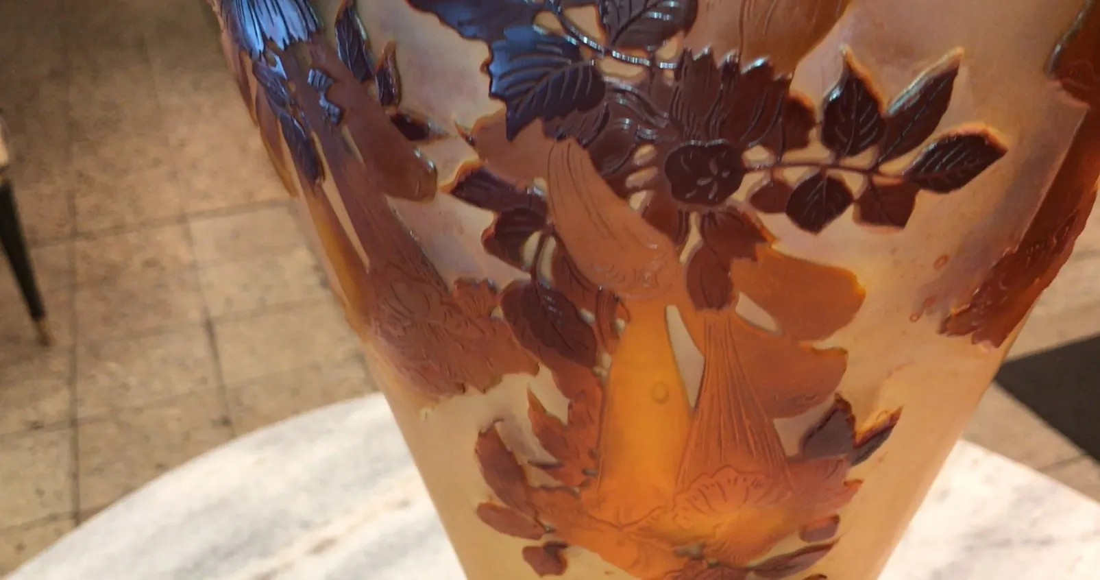 زجاج قديم موقع جالي بتصميم زهور بارز معروض في بيئة أنيقة.