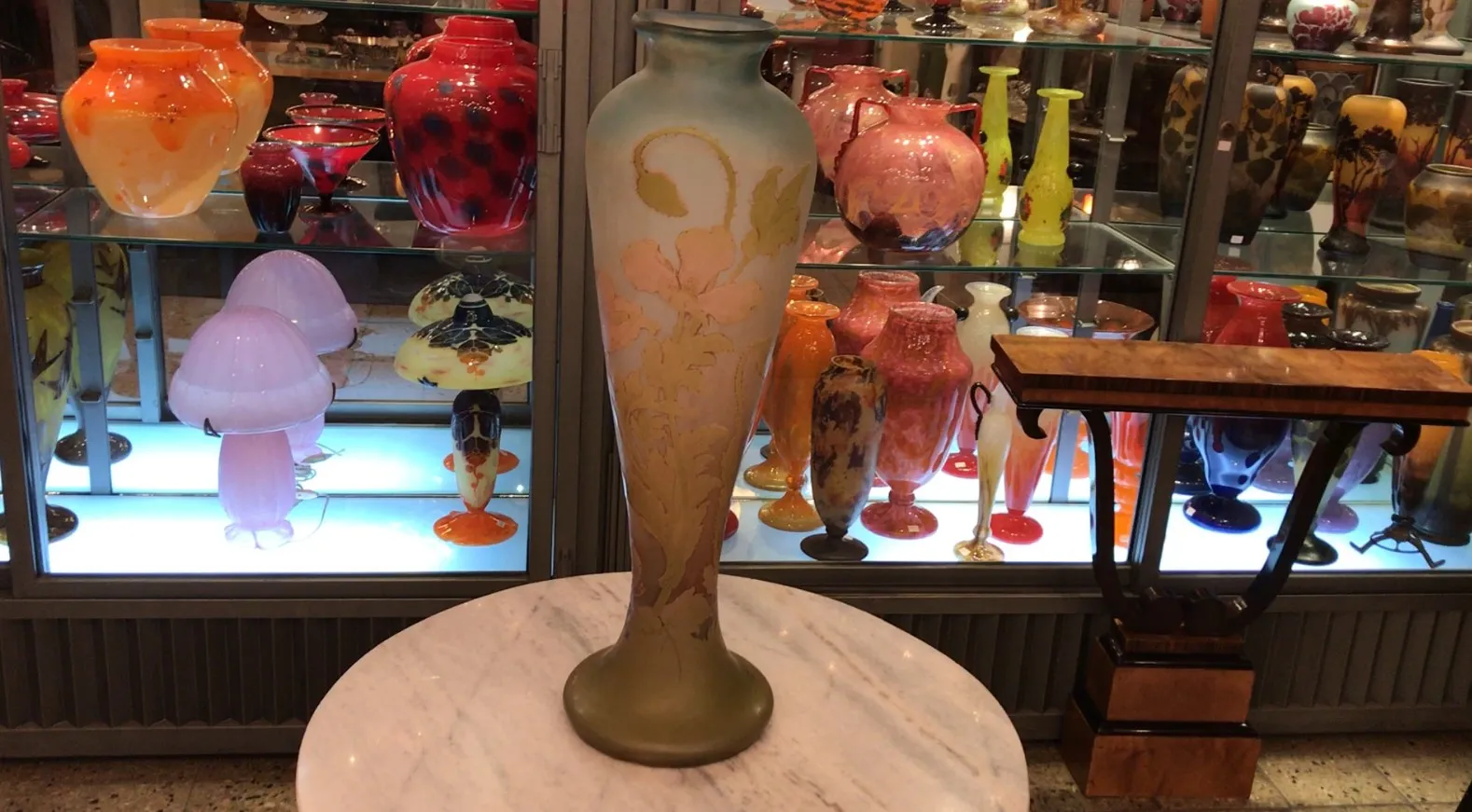 SIGNED GLASS Gallé displayed among colorful antiques.