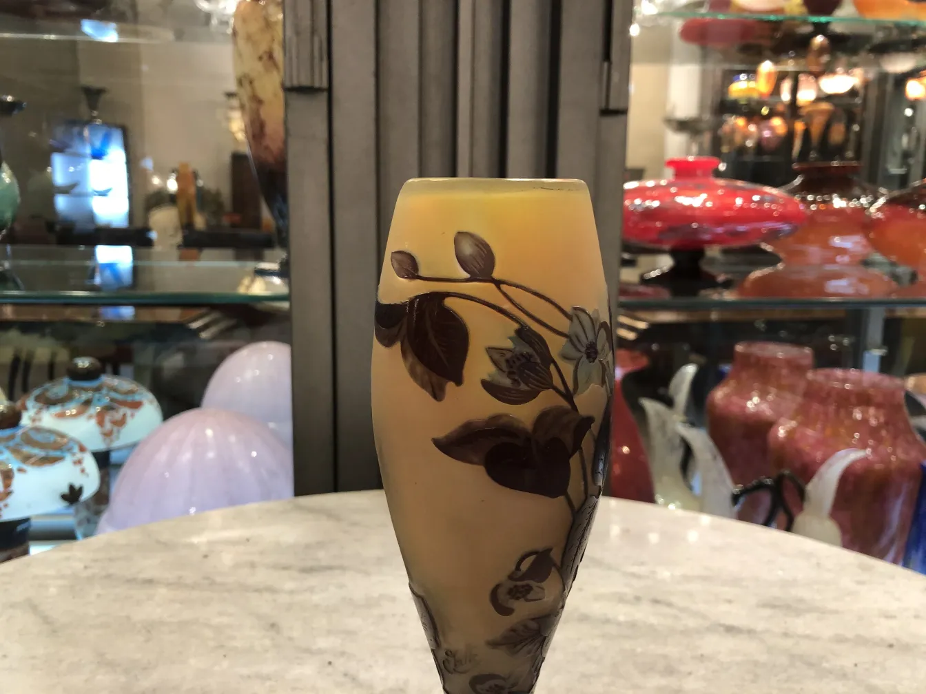 Decorated signed glass vase by Gallé, displayed among antique glass.