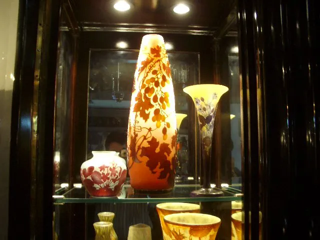 Antique signed glass Gallé piece, decorated with vibrant colors, displayed in a showcase.