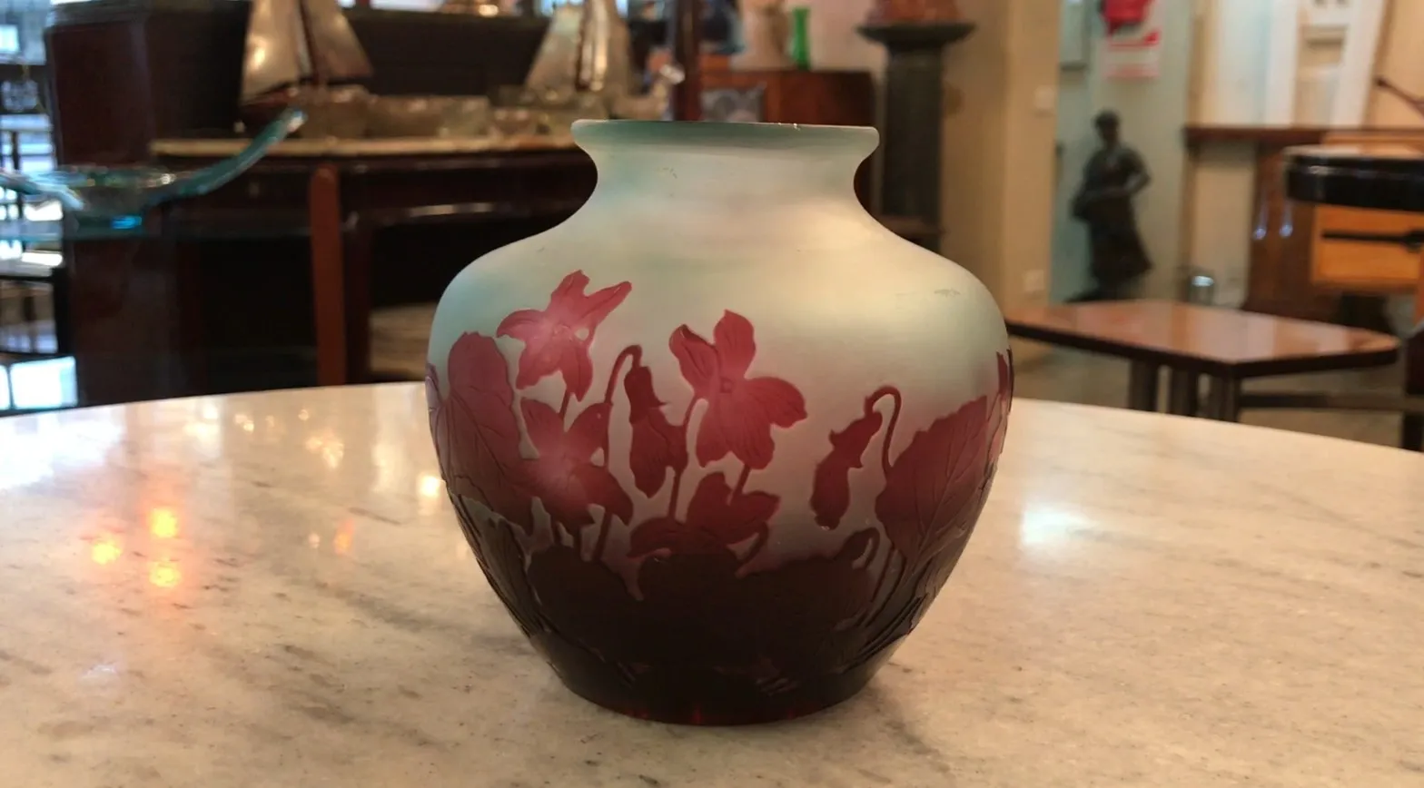 vaso antigo de vidro assinado Gallé com design floral, em uma mesa