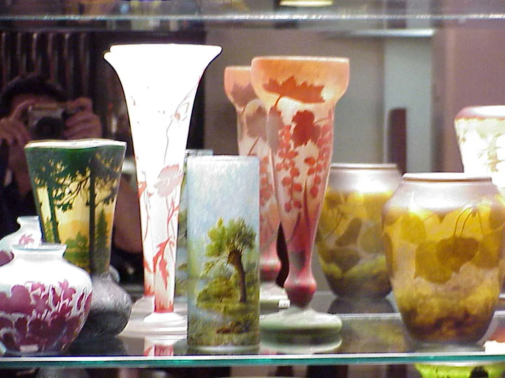 Vases en verre signé Gallé avec des décorations naturelles sur une étagère.