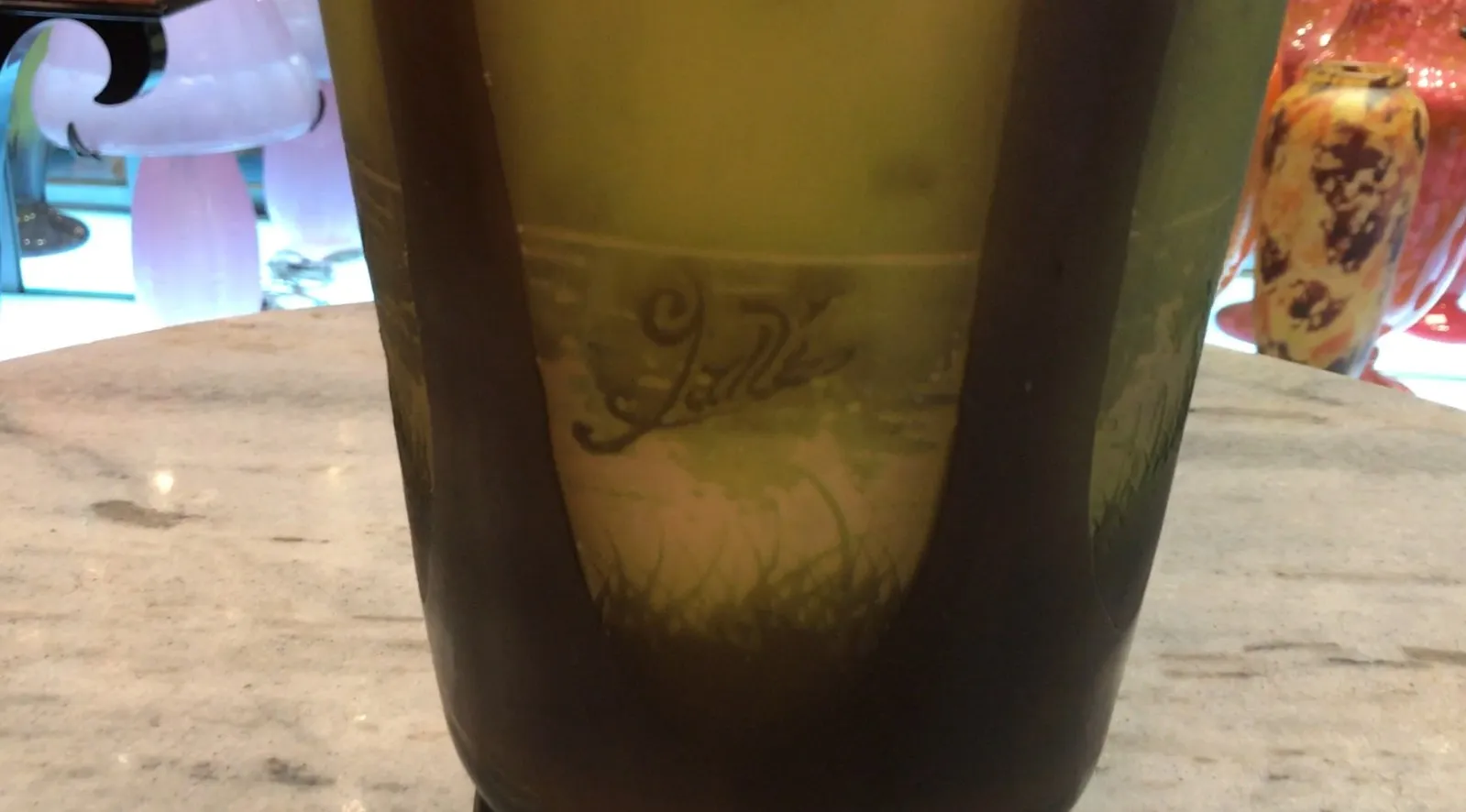 Antique signed glass Gallé with floral design in green and brown, elegant setting.