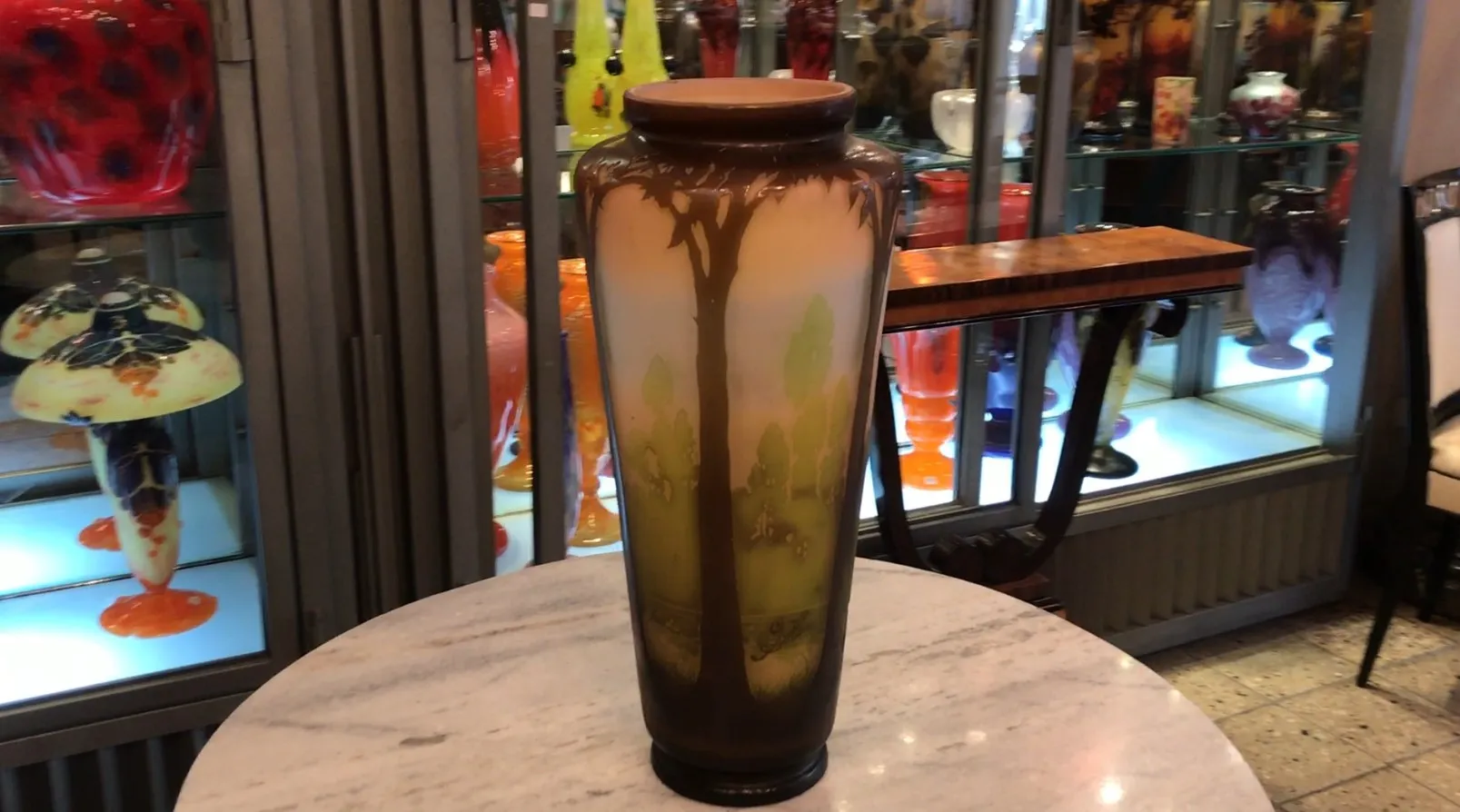 Antique Gallé signed vase, featuring trees and landscape, displayed among other antiques.