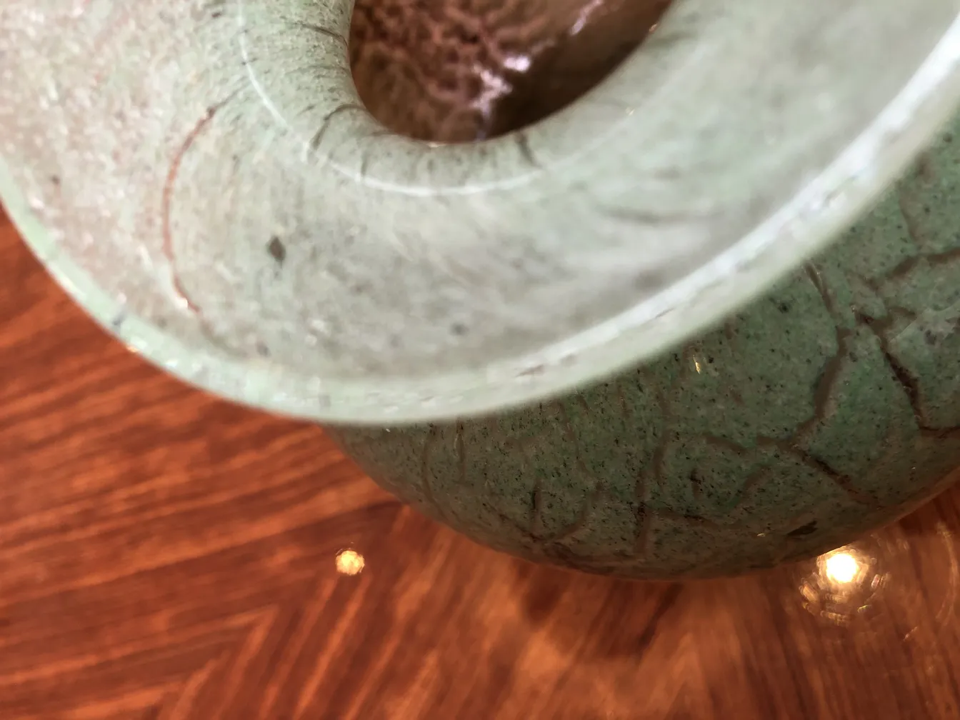 Detail of signed glass antique with distinctive design against wood background.