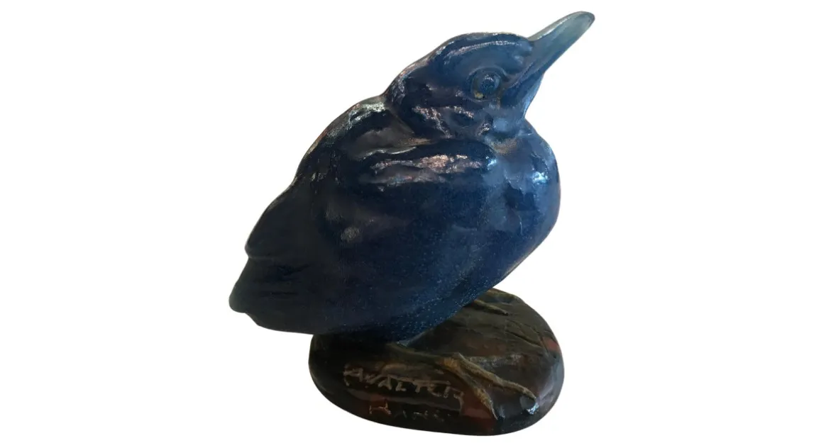 blue glass sculpture of a bird on a decorative base