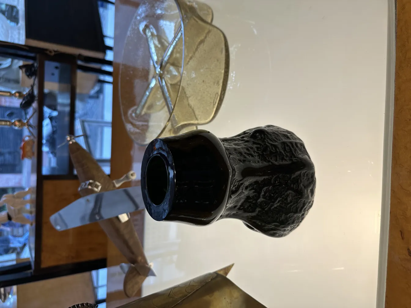 Vidro assinado com superfície intrincada e forma elegante, cercado por antiguidades.