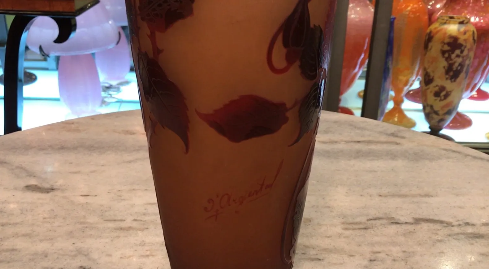 Vetro firmato D'Argental con design di foglie rosse su sfondo chiaro, in ambiente antico.