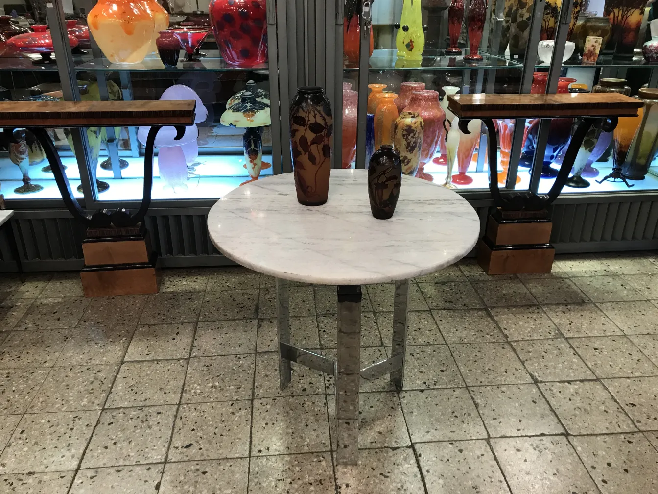 Vidro assinado D'Argental sobre mesa com decoração variada ao fundo