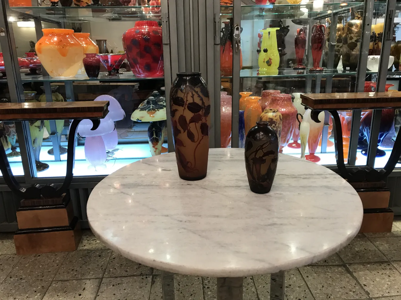 Dois vasos antigos de vidro assinado D'Argental sobre uma mesa.