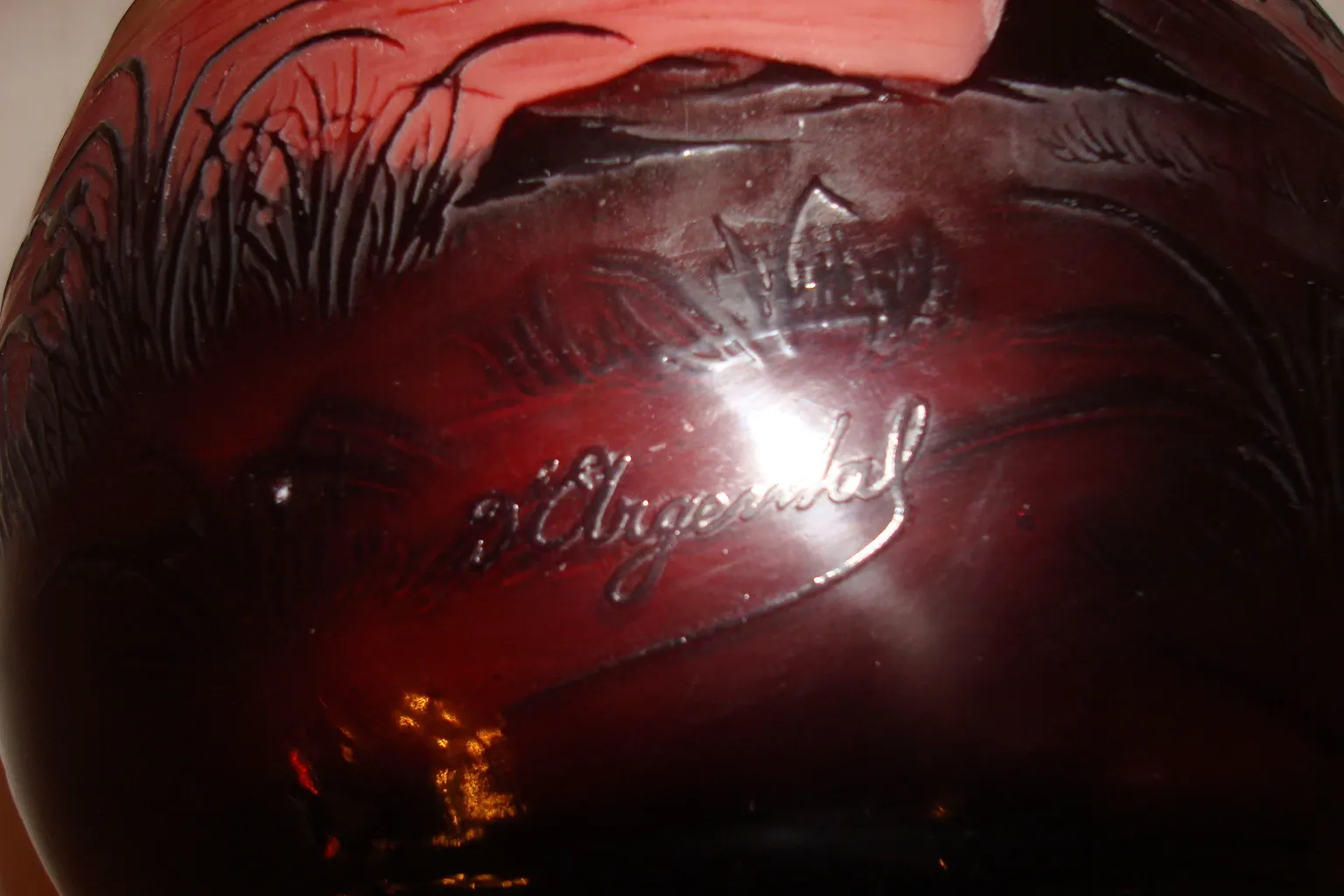 Verre ancien signé D'Argental avec des reflets rouges et une forme élégante.