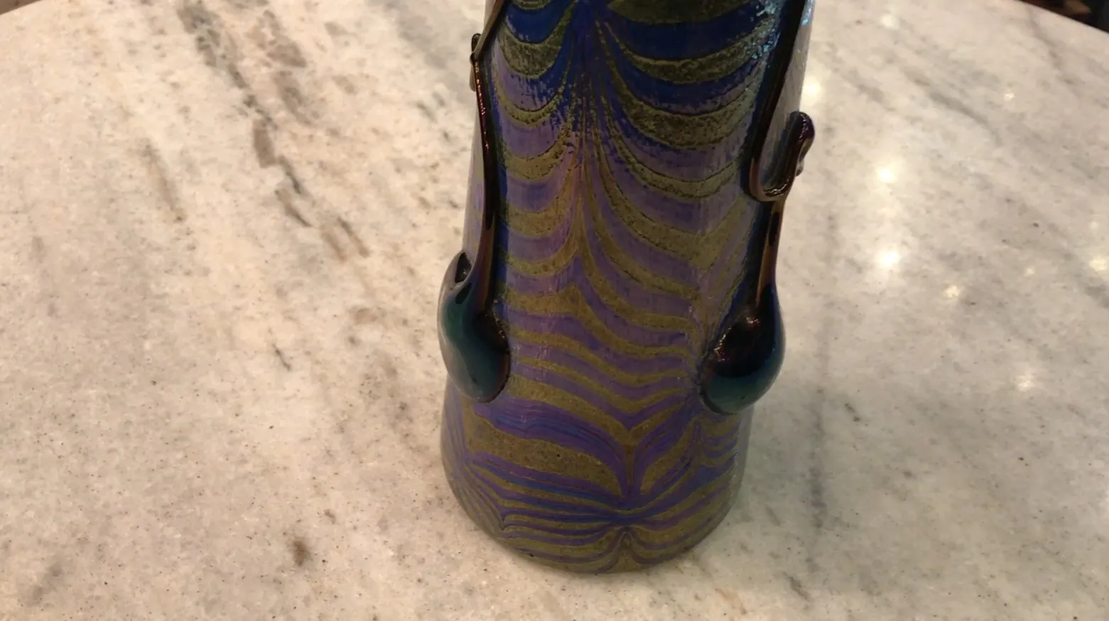 Antico vetro firmato Loetz con design colorato ed elegante, esibito in un ambiente sobrio.