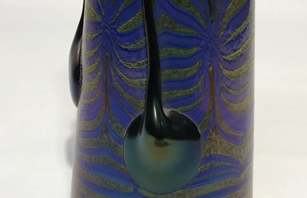 Vetro antico Loetz con disegni colorati e forme eleganti su uno sfondo chiaro.