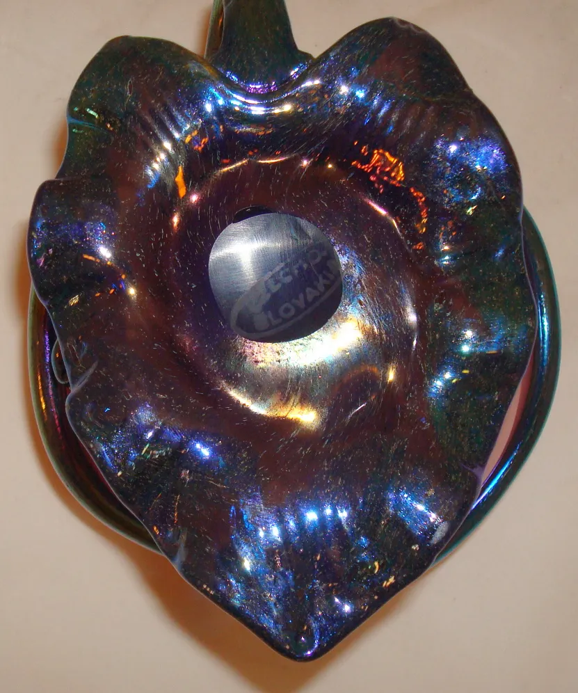 Decorative signed glass Loetz with a colorful, shiny design in a vintage setting.