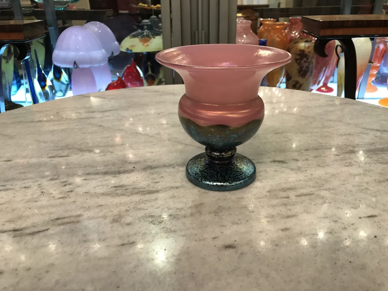 Colorful signed Loetz glass in elegant shape, surrounded by antiques.